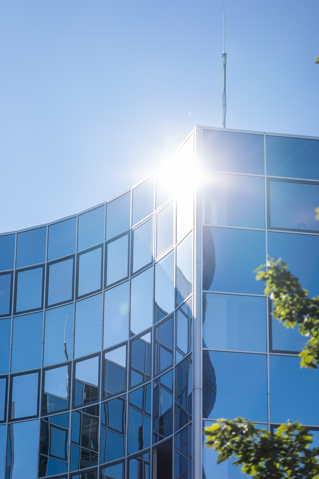 Sonne spiegelt sich in der geschwungenen Glasfassade